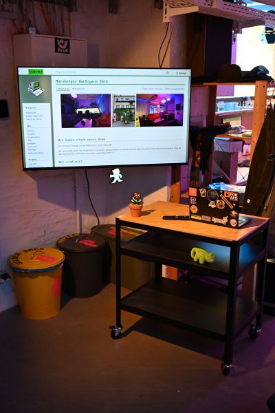 Datei:K4CG 2025 Loungebereich Vortragsbildschirm und Pult.jpeg